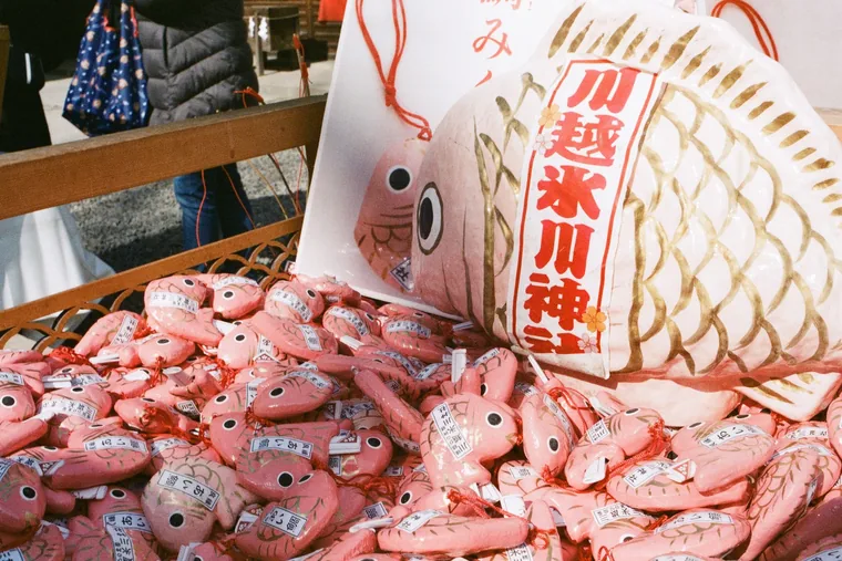 Pink sea-bream lucky charms piled at a shrine stall